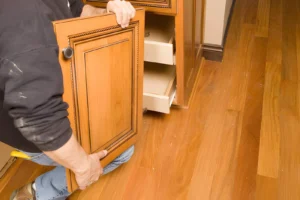 Contractor installing a cabinet door during a kitchen cabinet refacing project